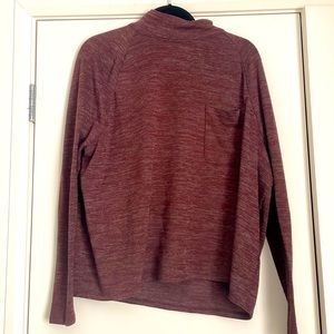 Burgundy colored long sleeved high neck top with front pocket on the chest.